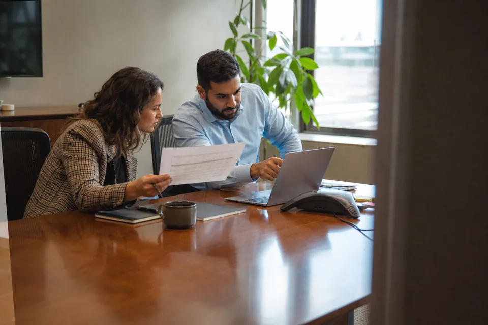 IT lead and finance manager comparing a software quote at a conference table