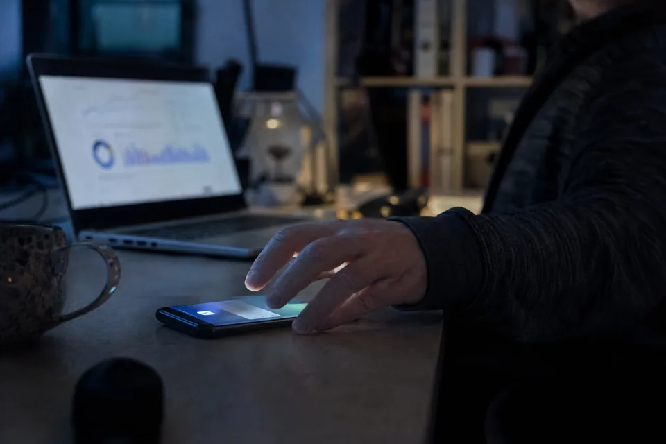 Phone on a desk lighting up with a deliverability alert at night next to a laptop