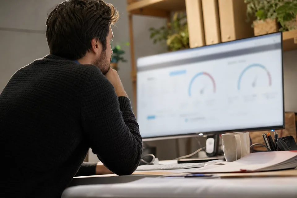 Email marketer reviewing sender reputation gauges on a large monitor in a bright office