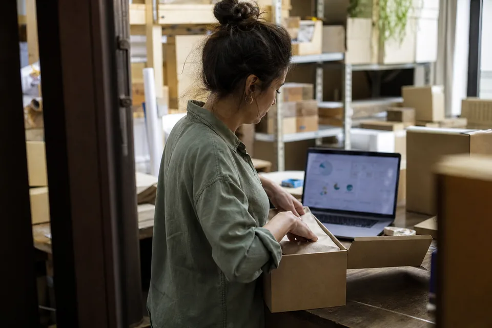Ecommerce marketer working on a laptop in a bright warehouse office before a sale