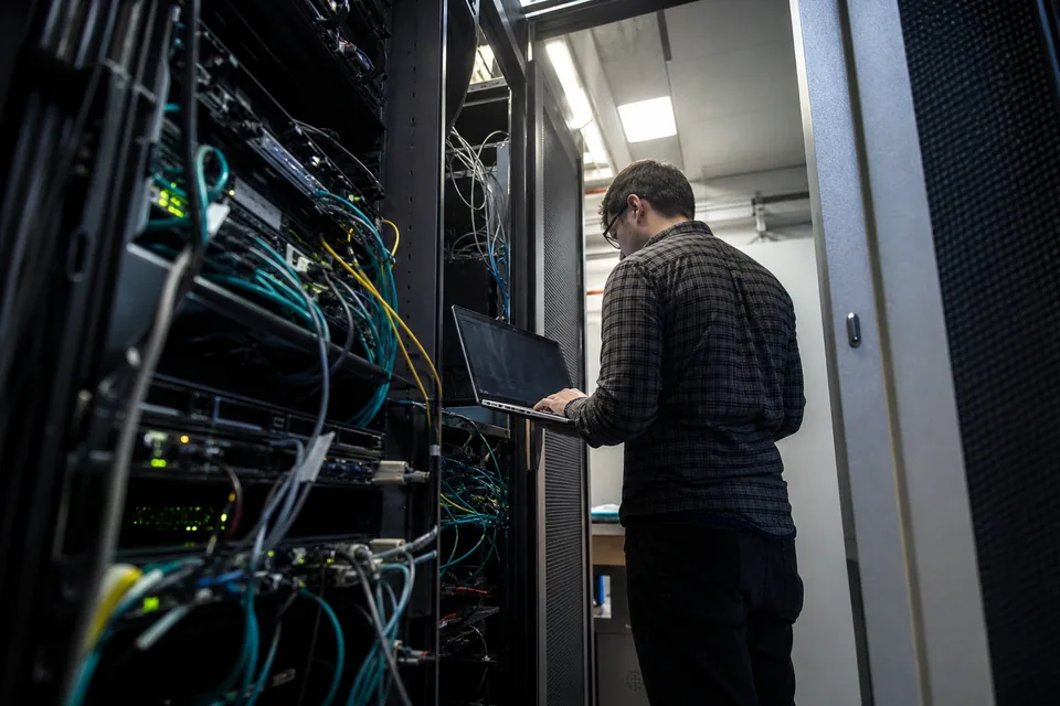 Server room aisle in cool white light with racks of network equipment
