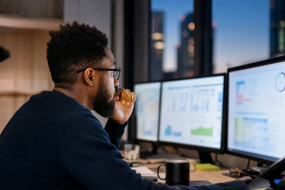 Email operations lead at a desk with two monitors at dusk
