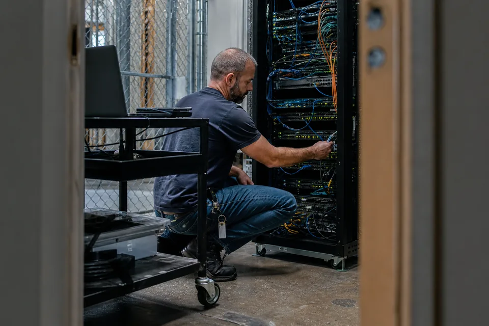 Network engineer patching a switch in a hosting company server rack