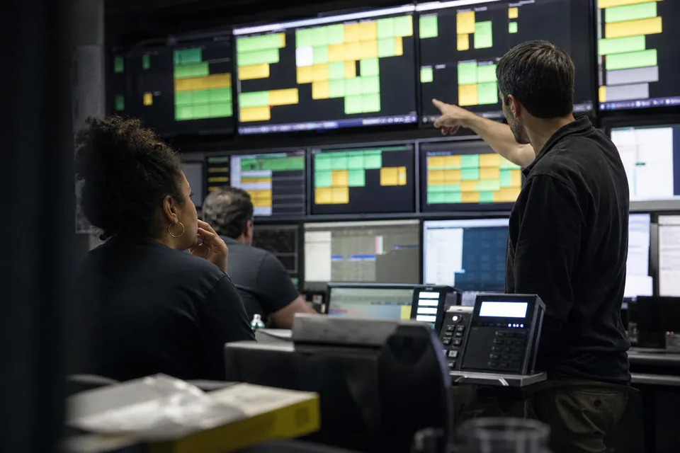 Marketing team discussing a deliverability chart around a monitor